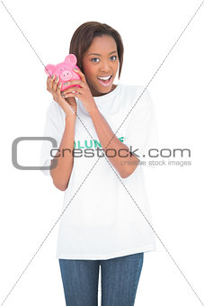 Smiling woman shaking piggy bank by her ear