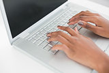 Close up on womans hands typing on her laptop