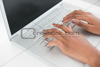 Close up on womans hands typing on her laptop