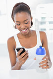 Smiling athletic woman looking at her smartphone