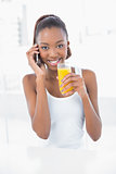 Happy athletic woman phoning while holding orange juice