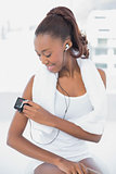 Smiling athletic woman changing music on her mp3