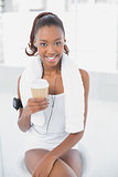 Relaxed athletic woman listening to music holding coffee
