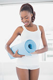 Slender athletic woman holding exercise mat