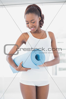 Slender athletic woman holding exercise mat