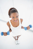 High angle view of happy fit woman exercising with dumbbells