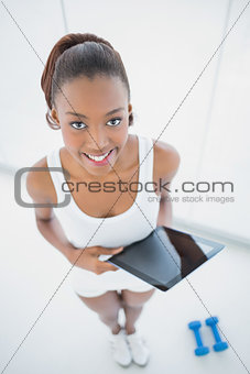 High angle view of happy sporty woman holding tablet