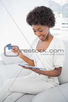 Smiling attractive brunette using her tablet pc to buy online