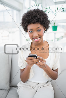Smiling gorgeous brunette using her smartphone