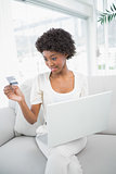 Focused gorgeous woman using her credit card to buy online