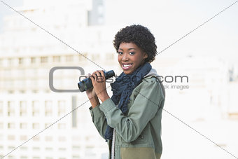 Smiling casual model holding binoculars