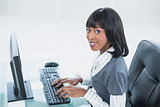 Smiling classy businesswoman typing