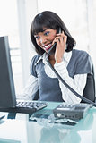 Smiling stylish businesswoman on the phone while working on computer