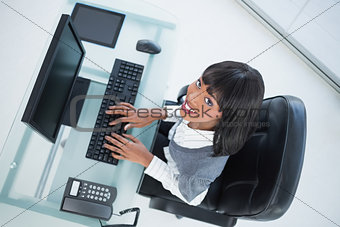 Overhead of smiling pretty businesswoman typing