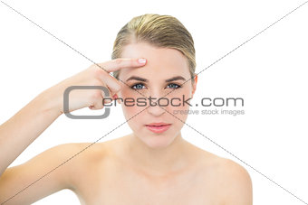 Pretty blonde pointing at wrinkle on her forehead
