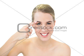 Smiling pretty blonde pointing at her eyebrow
