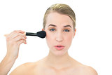 Content attractive blonde using blusher brush