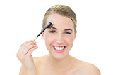 Smiling attractive blonde using eyebrow brush