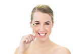 Smiling attractive blonde holding eyelash curler
