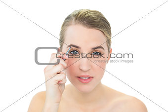 Attractive blonde using tweezers on her eyebrow