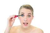 Concentrated attractive blonde applying mascara