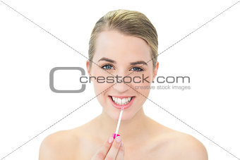 Smiling attractive blonde applying lip gloss