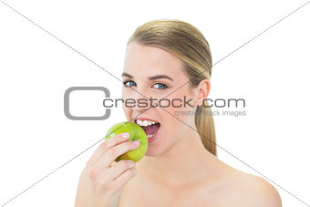 Smiling attractive blonde eating green apple