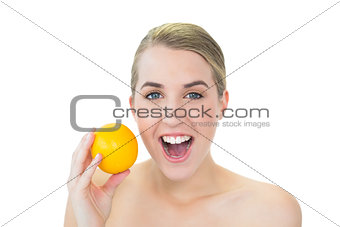 Surprised attractive blonde holding orange