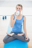 Cheerful pretty blonde in lotus position drinking water