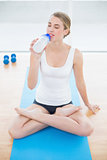 Sporty woman in lotus position drinking water