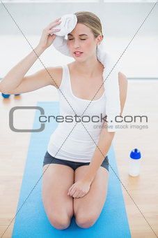Exhausted fit woman on her knees wiping her forehead