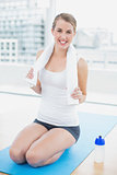 Cheerful fit woman on her knees on sport mat posing