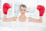 Smiling competitive woman with red boxing gloves cheering up