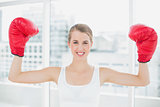 Cheerful competitive woman with red boxing gloves cheering up