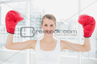 Cheerful competitive woman with red boxing gloves cheering up