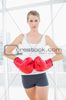 Competitive woman with red boxing gloves posing