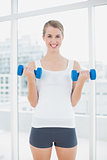 Smiling fit woman exercising with dumbbells