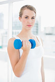 Thoughtful fit woman exercising with dumbbells