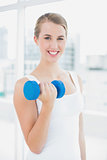 Cheerful fit woman exercising with dumbbells