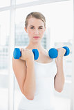 Content fit woman exercising with dumbbells