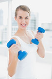 Sporty smiling woman exercising with dumbbells