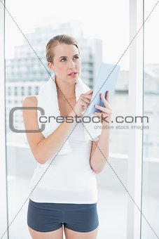 Pensive sporty woman using tablet pc