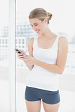 Cheerful sporty woman text messaging
