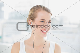 Head shot of smiling sporty woman listening to music