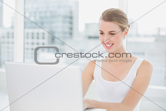 Smiling blonde using her laptop