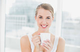 Smiling blond woman holding cup of coffee