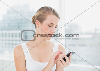 Focused blond woman text messaging