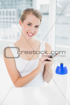 Smiling blond woman sending a text message