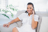 Smiling woman in white dress having a phone call