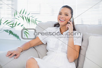 Happy woman in white dress having a phone call